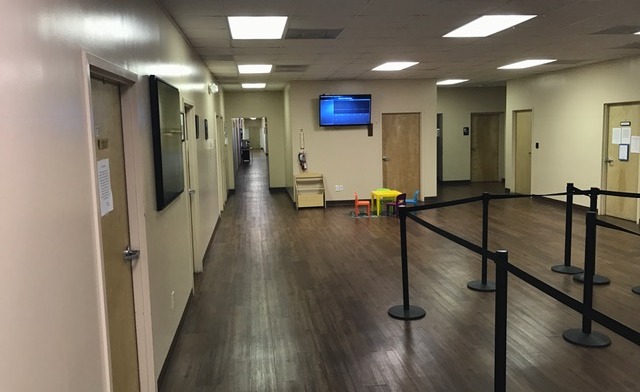 Interior hallway with entrance doors, professional flooring, wall-mounted monitor, and queue management barriers