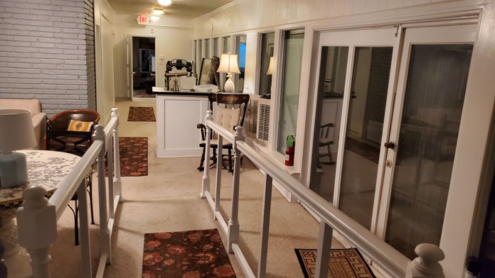 Interior corridor with white painted walls, wooden doors, handrails, and administrative desk