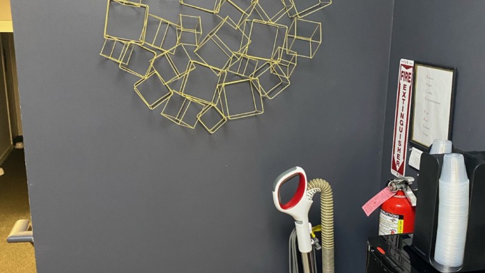Interior wall feature with abstract gold-framed geometric art, gray painted walls, and storage elements