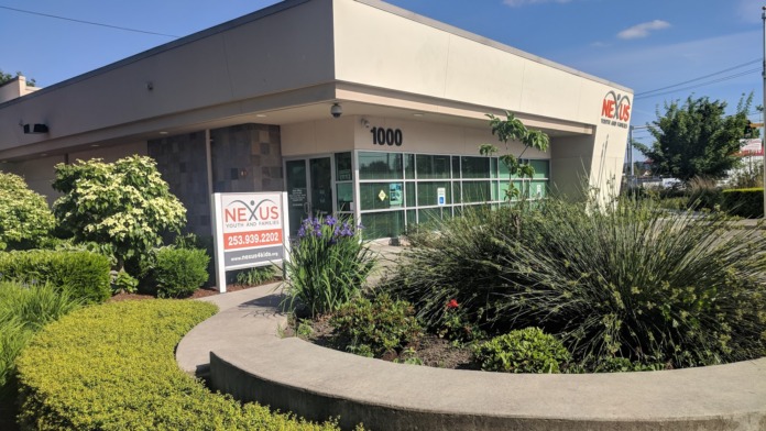 Facility entrance showing curved concrete planter with ornamental grasses, shrubs, and front facade