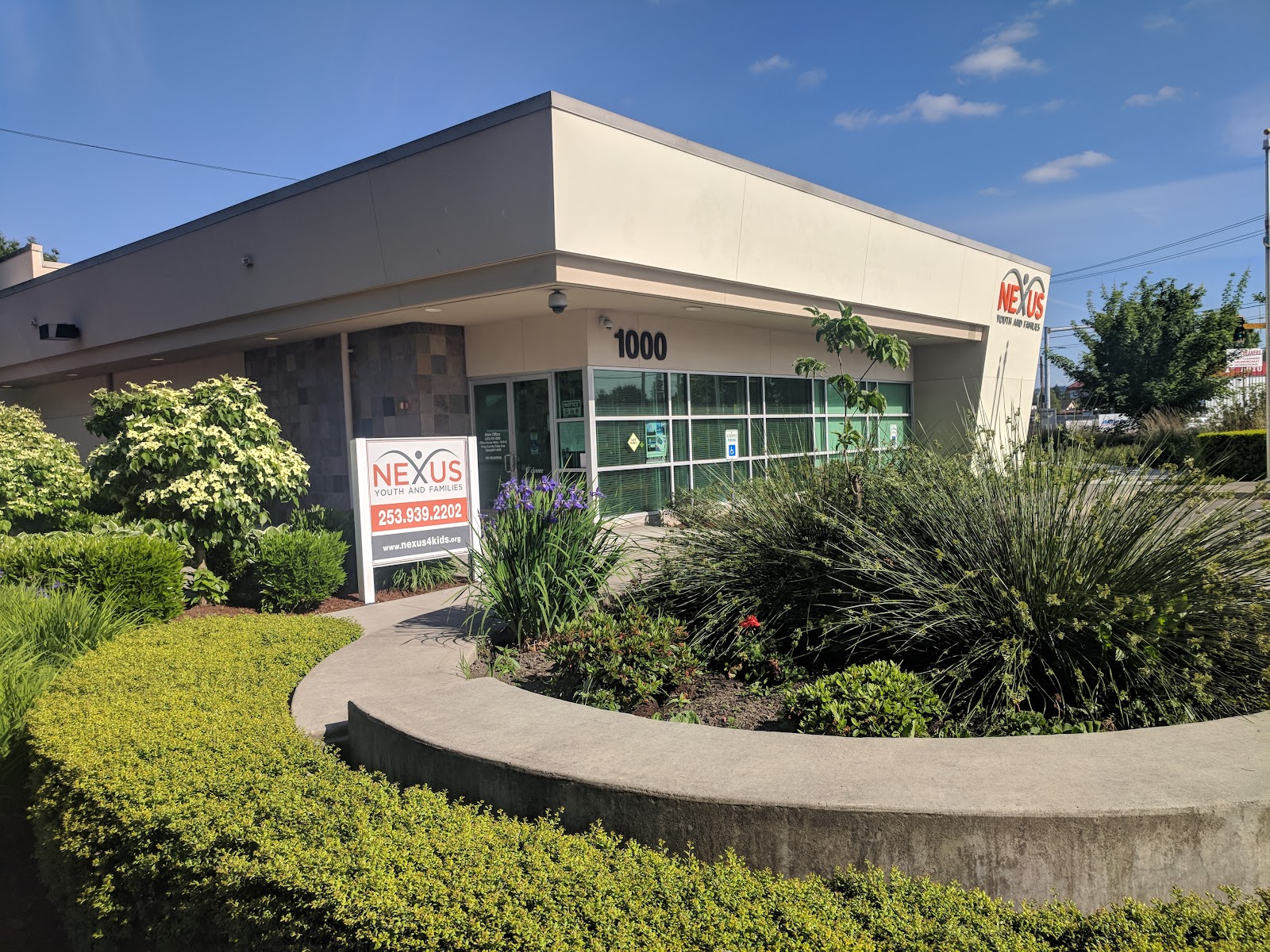 Facility entrance showing curved concrete planter with ornamental grasses, shrubs, and front facade
