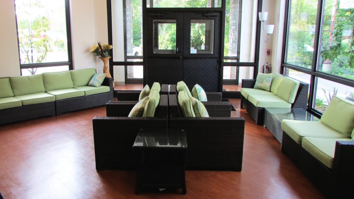 Interior lobby with high ceilings, glass entrance doors, and lime-green upholstered seating arrangements.