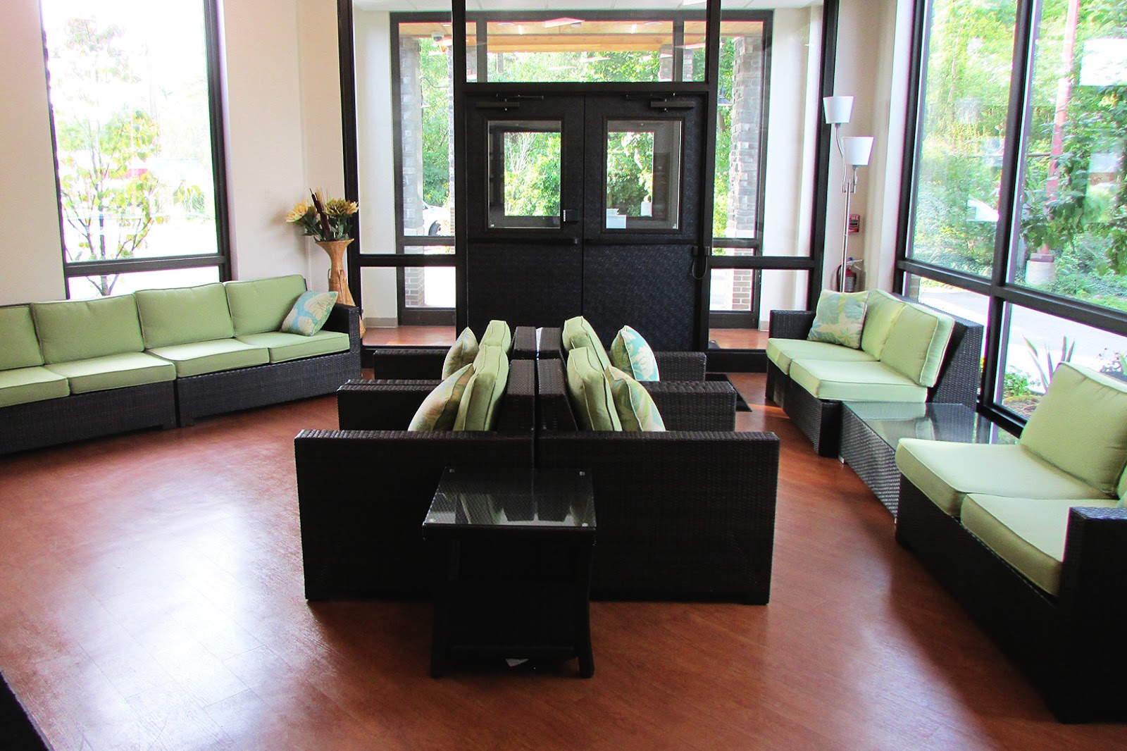 Interior lobby with high ceilings, glass entrance doors, and lime-green upholstered seating arrangements.
