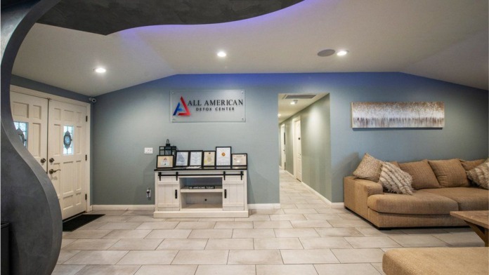 Interior treatment center lobby with All American Detox signage, contemporary furnishings, and architectural ceiling accents.