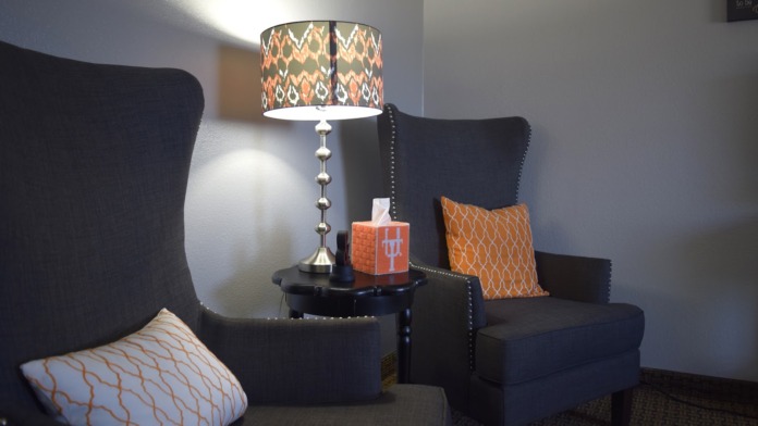Interior lounge with black upholstered chairs, decorative lamp with patterned shade, orange pillow accents