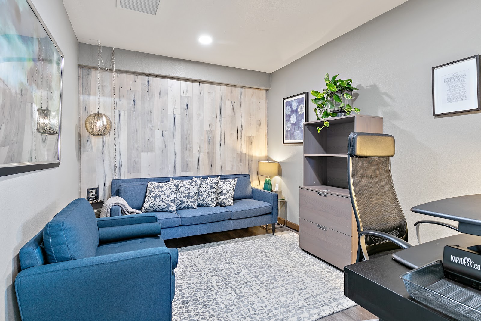 Interior lounge space with blue sofa, accent chairs, large windows with decorative panels, and modern furnishings
