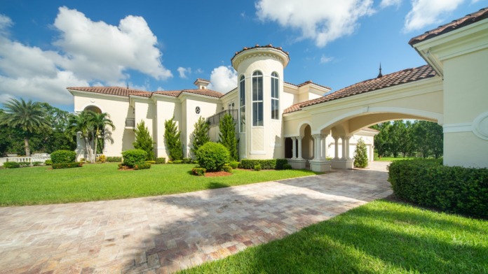 Exterior view of elegant cream and white treatment facility with circular tower, manicured landscaping, and brick driveway approach