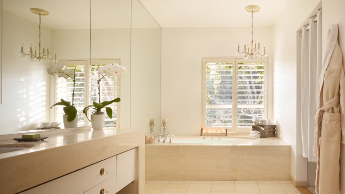 Interior bathroom with soaking tub, dual vanity with mirrors, chandeliers, and marble finishes