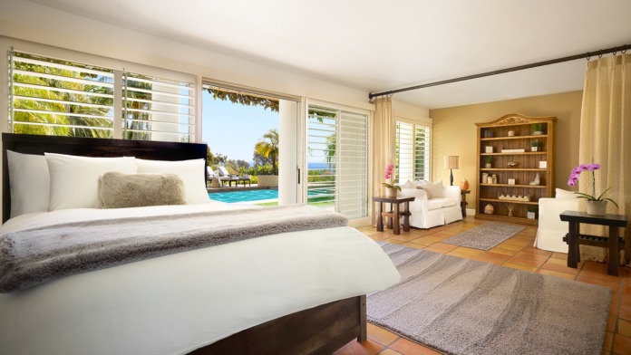 Interior bedroom with king bed, sitting area, and ocean view through large sliding glass doors