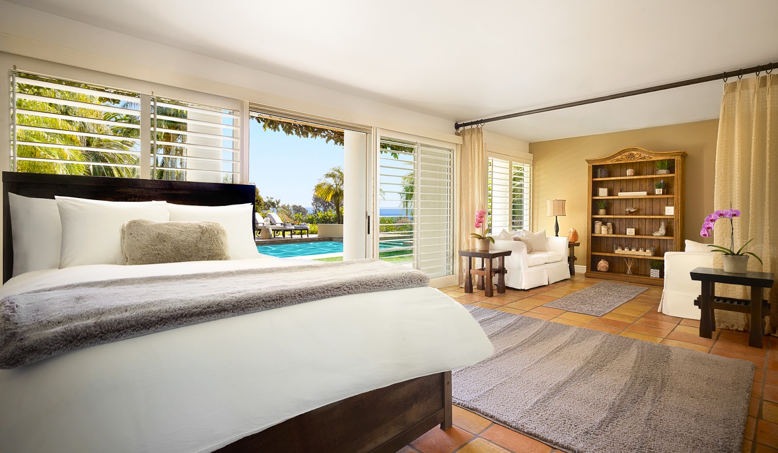Interior bedroom with king bed, sitting area, and ocean view through large sliding glass doors