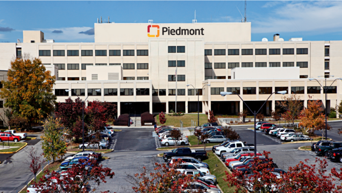 Exterior view of Piedmont Macon Medical Center main building with large Piedmont signage, parking area with vehicles, and landscaped grounds