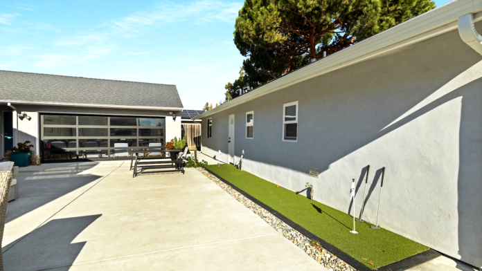 Exterior courtyard showing paved parking, gray stucco buildings with glass garage doors, and landscaped green spaces