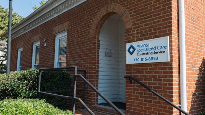 Exterior front of brick building with arched entryway, white door, facility signage and phone number displayed