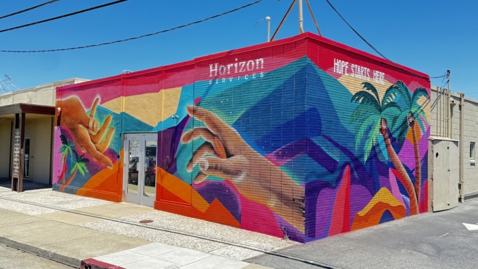 Exterior showing colorful painted building facade with Horizon Services branding and motivational messaging on street corner