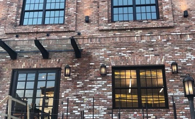 Exterior view of brick treatment facility building with large windows, entrance stairs with metal railings, and address 411 Van Brunt Street visible