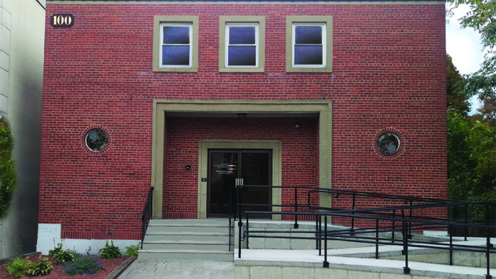 Exterior of red brick treatment center showing main entrance with covered portico, accessible ramp, and glass doors.