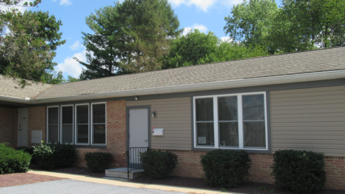 Exterior view of treatment facility main entrance with brick and siding construction, large windows, entrance door, and landscaping