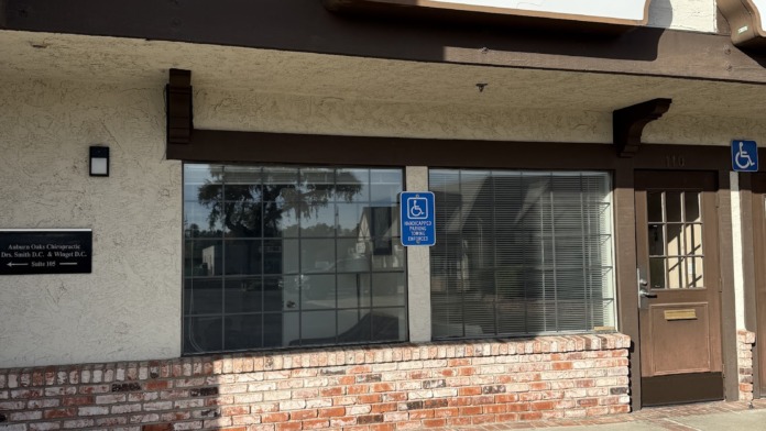 Exterior showing Lumen Health Services building entrance with signage, glass doors, brick base, and accessible parking indicator.