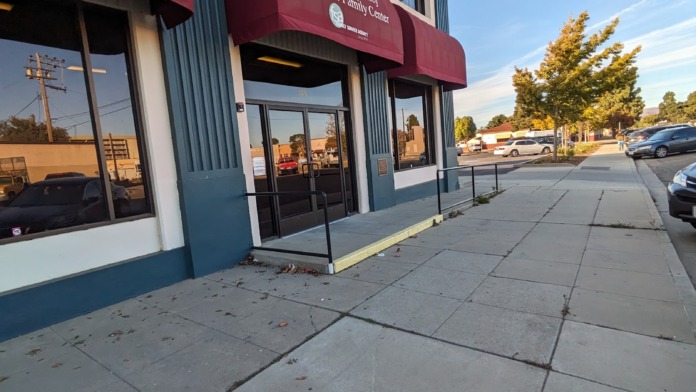 Exterior of Santa Maria Valley Youth & Family Center showing maroon awning, glass entrance doors, and facility signage on brick and metal building