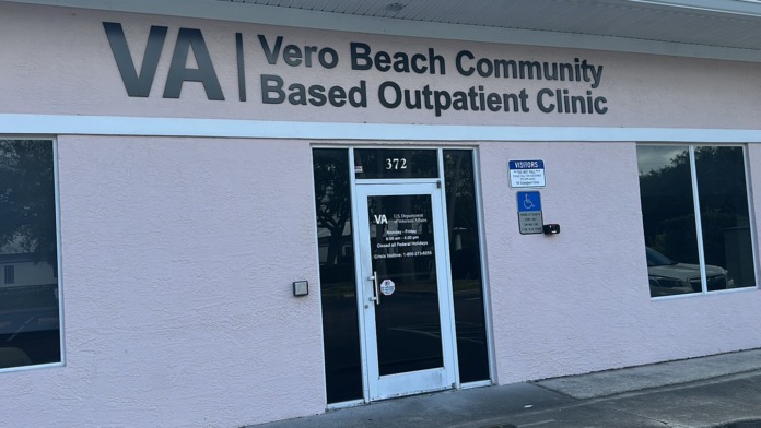 Exterior view of white clinical building with VA Vero Beach Community Based Outpatient Clinic signage, entrance door, and street-facing windows