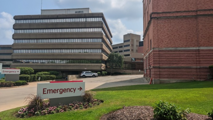 Exterior view of treatment facility showing main entrance with emergency directions, landscaped grounds, and brick building facade