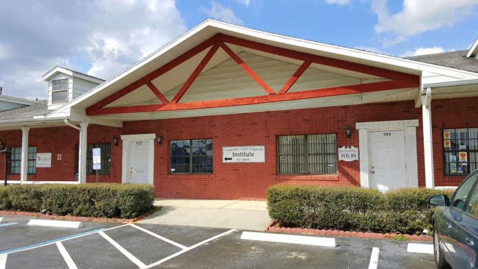Exterior view of red brick treatment facility with white trim, covered entrance, and landscaped grounds on Sterling Road