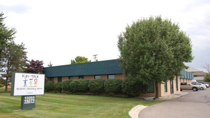 Exterior view of Kids-TALK Children's Advocacy Center building with entrance sign, landscaping, and parking area