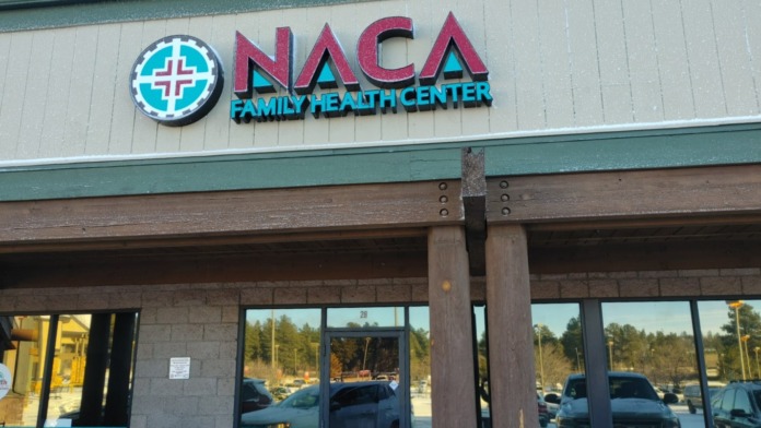 Exterior front entrance of NACA Family Health Center with prominent signage, parking area, and building facade