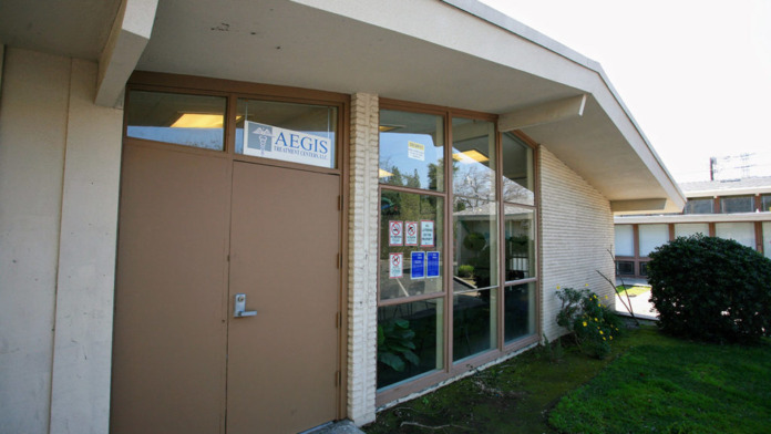 Exterior view of treatment facility entrance with AEGIS signage, glass doors, brick facade, and landscaping