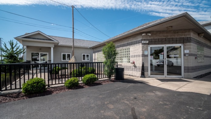 Exterior front facade of modern recovery facility with brick construction, landscaping, iron railing, and entrance