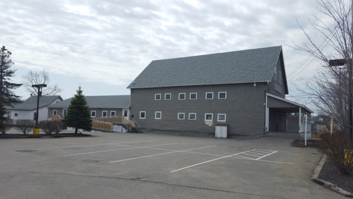 Exterior view of treatment facility showing main building facade, parking area with painted spaces, and wooden entrance ramp