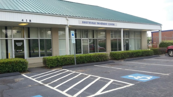 Exterior view of single-story treatment center with entry doors, windows, landscaping, and accessible parking spaces