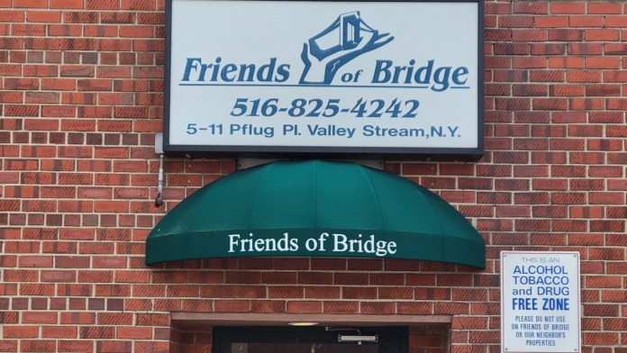 Exterior entrance with green awning, white signage, and posted alcohol and drug-free zone notice on red brick