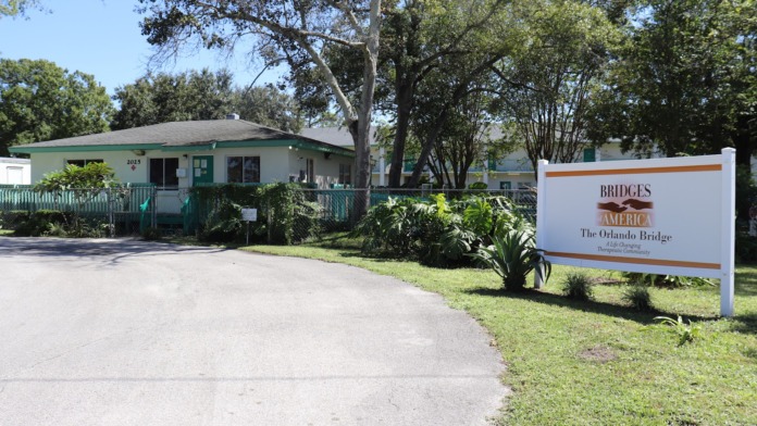 Exterior front view showing main entrance building, driveway, and Bridges America The Orlando Bridge facility sign with landscaping