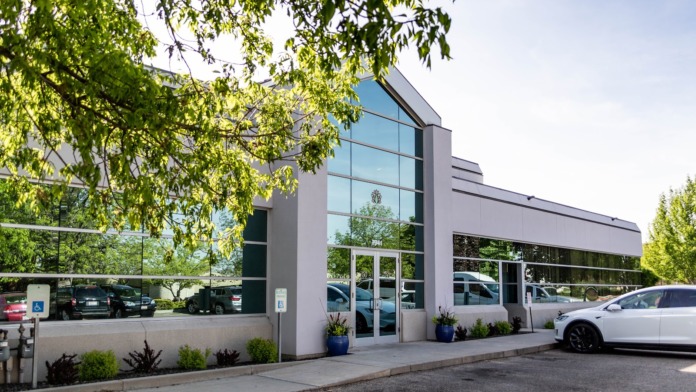 Exterior front entrance of treatment facility showing modern building facade, glass doors, parking area, and mature tree