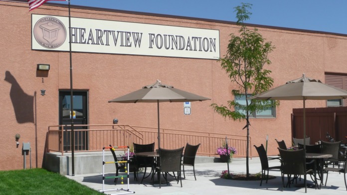 Exterior brick building with Heartview Foundation signage, American flag, and outdoor dining area with umbrella-shaded tables