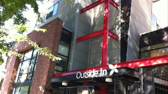 Exterior entrance of facility showing red and black signage, glass doors, and brick building facade