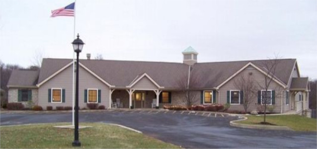 Exterior view of treatment center main building with stone and siding, American flag, covered entrance portico, and parking area