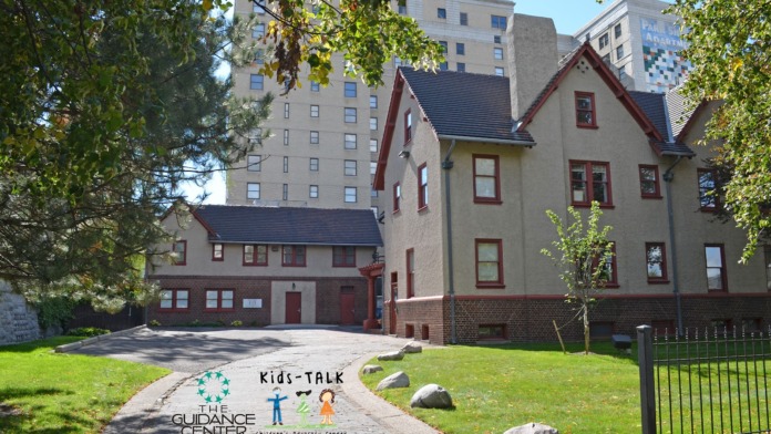 Exterior view of Kids-TALK Children's Advocacy Center building entrance with facility signage, landscaping, and brick facade