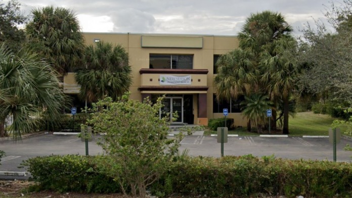 Exterior of tan treatment center building with palm trees, landscaping, parking area, and main entrance signage