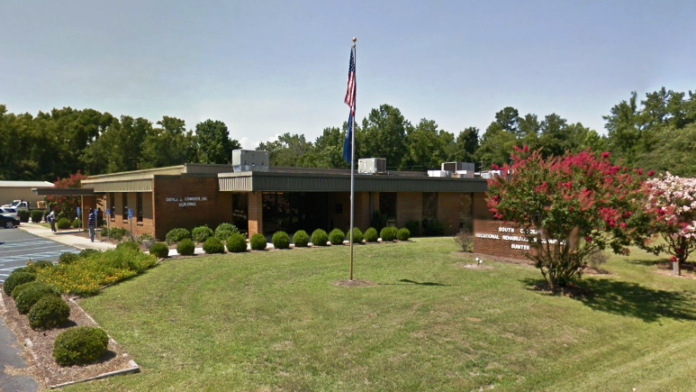 Exterior of single-story brick vocational rehabilitation building with American flag, landscaping, and lawn area.