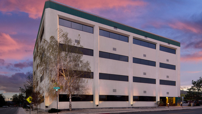 Exterior of four-story white behavioral health facility with green roof trim, horizontal bands, and address number 85 visible