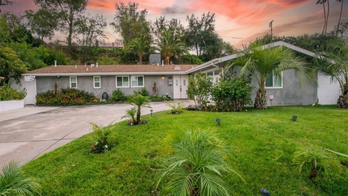 Exterior single-story treatment facility building with white walls, landscape grounds, palm trees, and hillside setting.