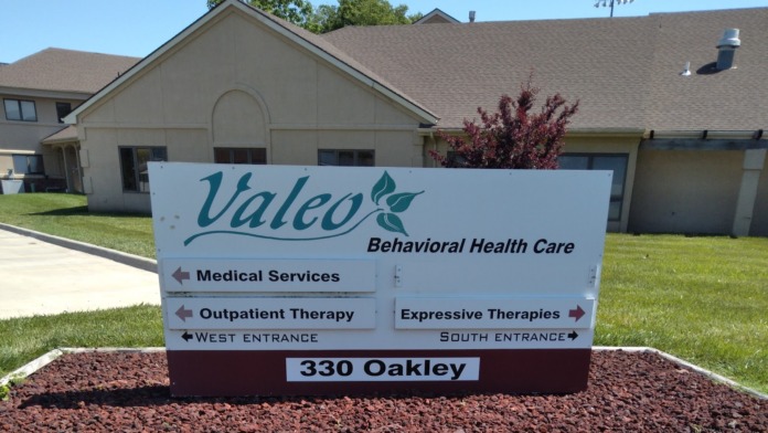 Exterior directional signage for Valeo Behavioral Health Care showing medical services and therapy entrances with facility building visible
