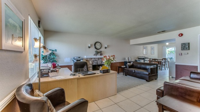 Interior reception lobby with wooden counter desk, leather seating, open layout, fireplace, and multiple seating zones for visitors