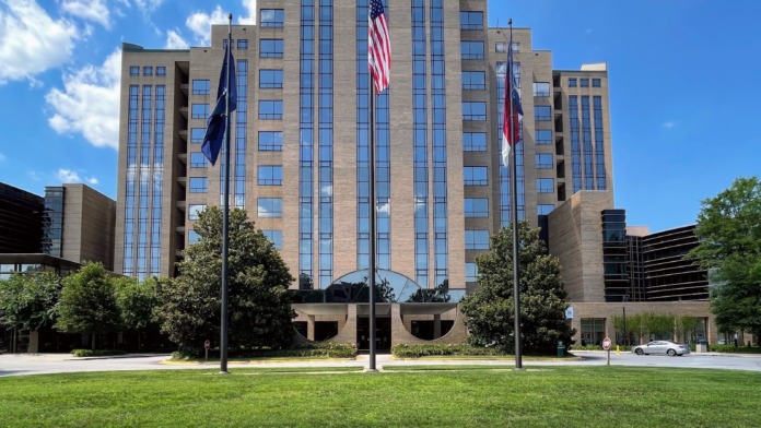 Exterior view of modern tan brick medical building with blue McLeod signage, manicured lawn, and architectural features