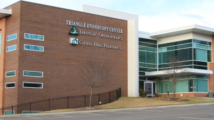Exterior of multi-story brick medical facility with windows, railings, and landscaping visible from street view.
