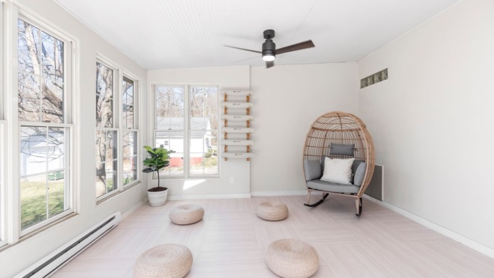 Interior peaceful space with large bay windows, woven meditation cushions on floor, hanging rattan chair, plant, and natural light for therapy and relaxation