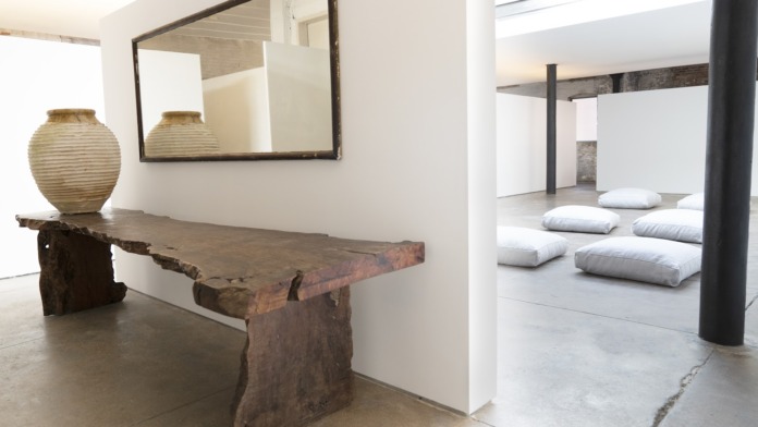 Interior zen space with decorative wooden bench, mirror, ceramic vessels, and minimalist design aesthetic
