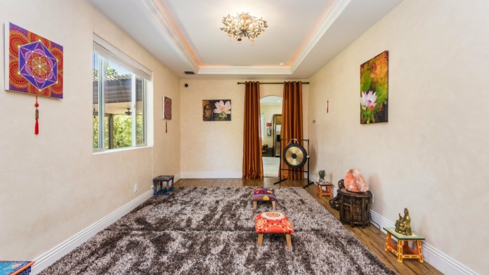 Interior meditation space with spiritual artwork, mandala tapestry, salt lamp, sound gong and windows
